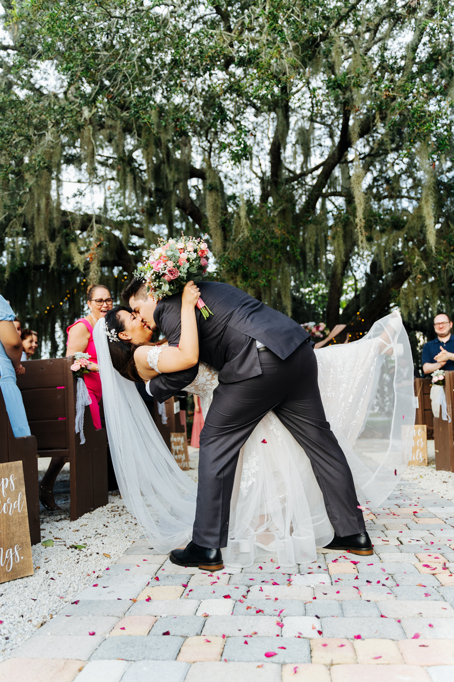 Happy groom dips the bride and kisses her at Ever After Farms Ranch